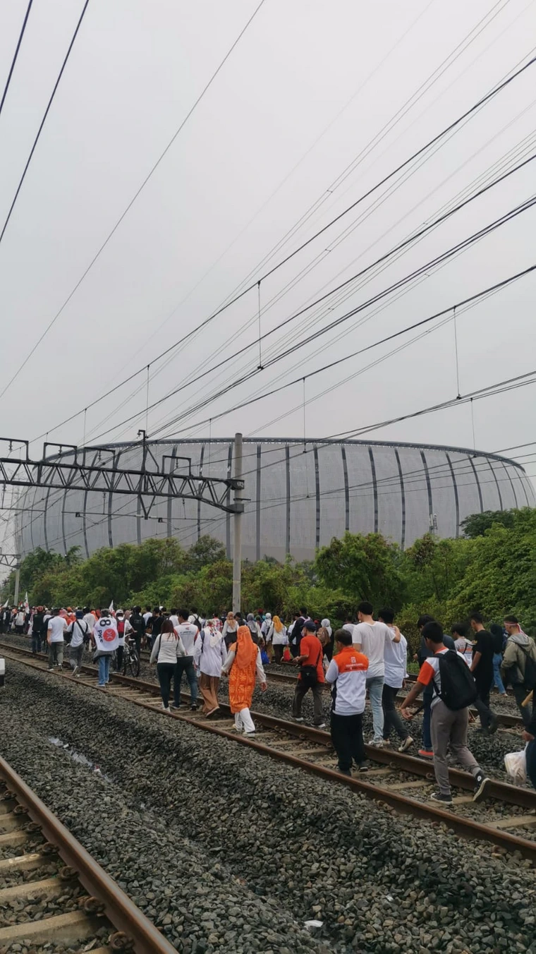 Nekat, Pendukung Anies dan Cak Imin Melintasi Rel Kereta untuk Sampai ke Stadion JIS